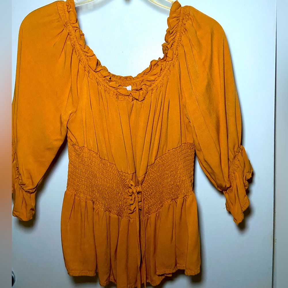 Long sleeve off the shoulder smock top with drawstring to adjust the waist.